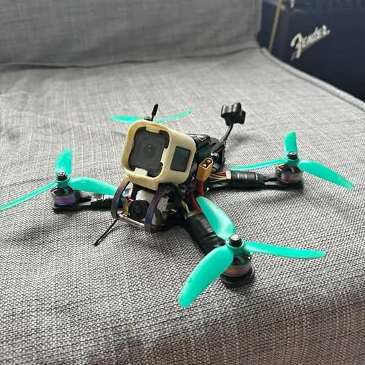 FPV quadcopter drone with green propellers and beige frame, front camera