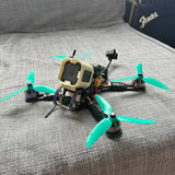 FPV quadcopter drone with green propellers and beige frame, front camera