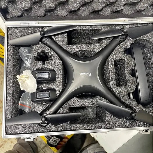 Quadcopter drone with four arms, matte black and gray finish, in a foam-lined case