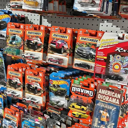 Assorted diecast model car toy packages on retail pegboard, various colors