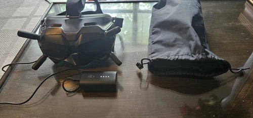 FPV goggles with detachable strap, battery, and power cable, in a carry bag