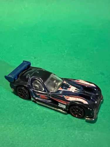 Hot Wheels diecast race car, dark body with colorful flame decals