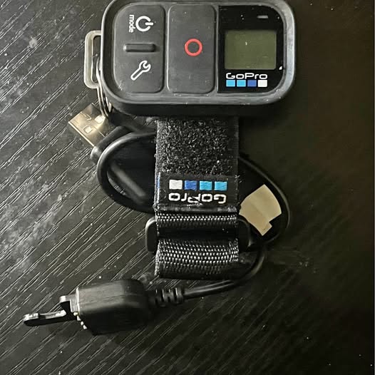 GoPro-style action camera in housing with mounting strap and cable connectors