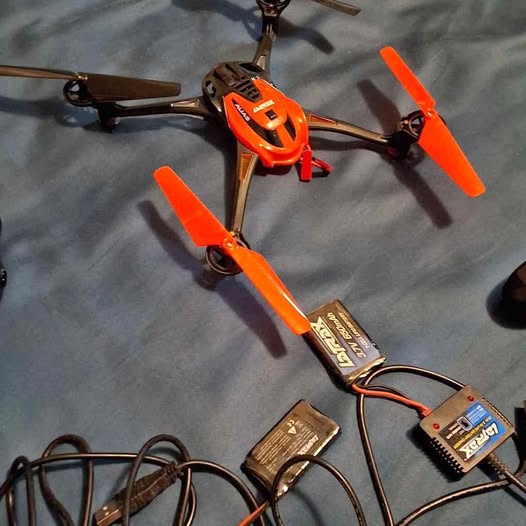 Orange quadcopter drone with four propellers and black landing gear, ready for flight