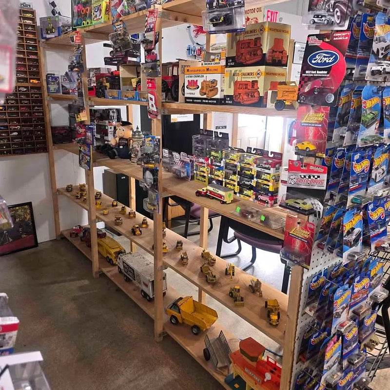 Diecast construction vehicle models on wooden display rack, assorted trucks and equipment