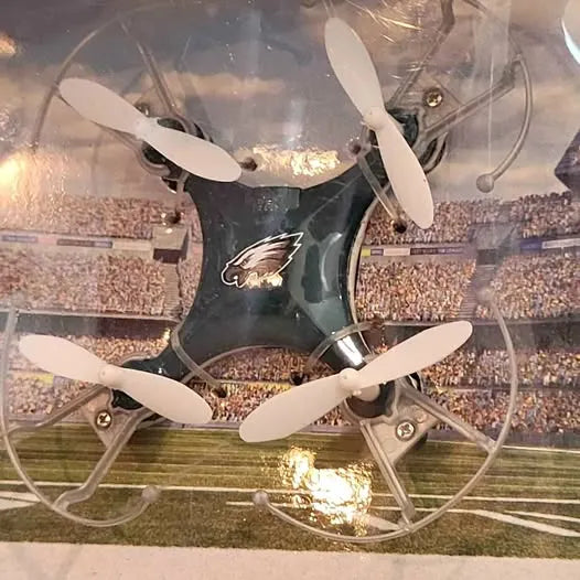 Mini quadcopter drone with black body, white propellers, eagle logo on the center