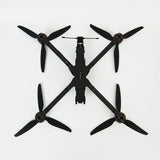 Black quadcopter racing drone with four propellers and central camera module