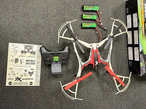 FPV RC drone with white/red frame and black controller, manuals included