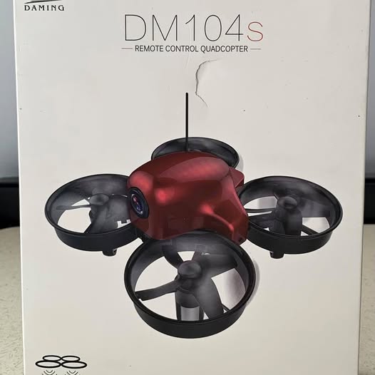 Mini red quadcopter drone with four black propellers and overhead camera mast
