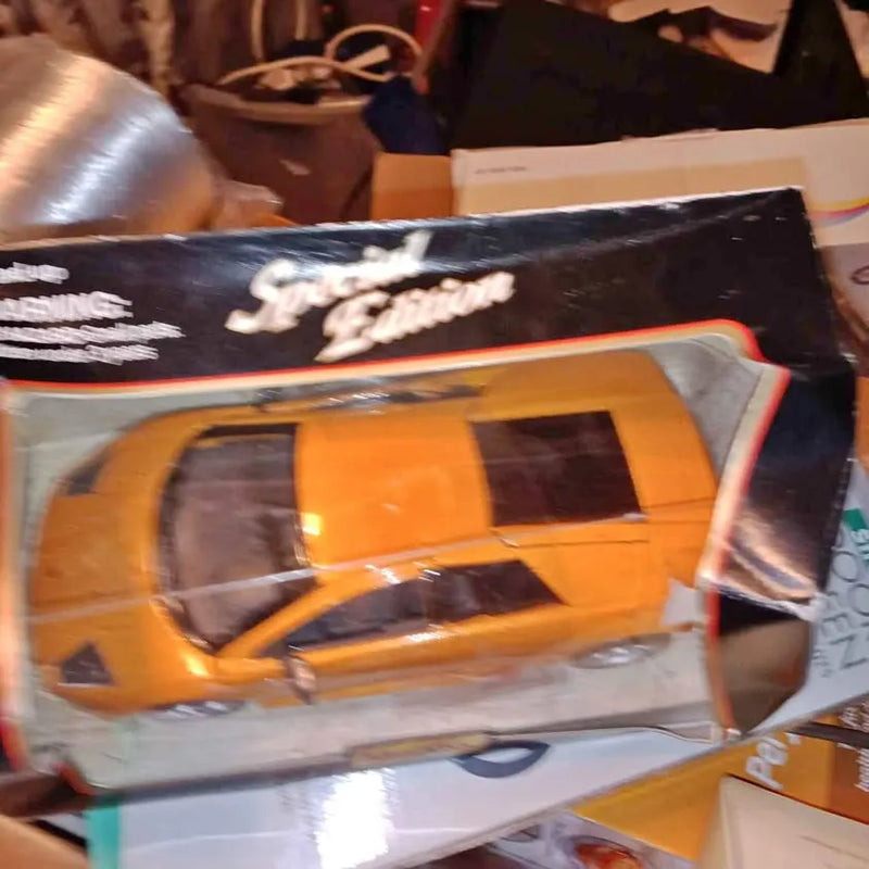 Orange diecast metal car with black details, shown in retail packaging window.