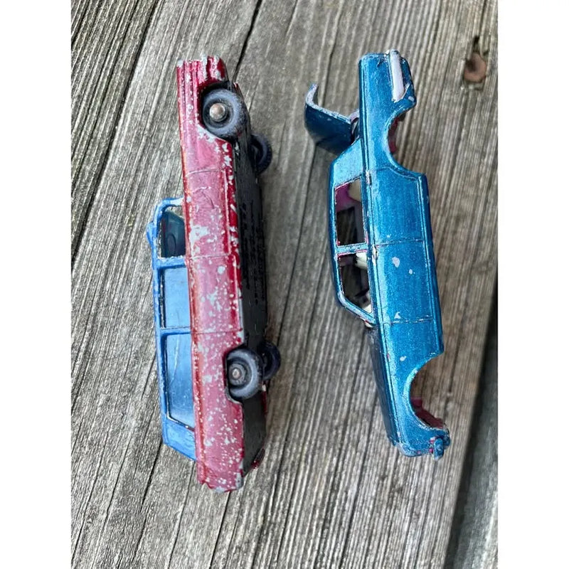 Vintage diecast toy cars, red and blue, side-by-side on display
