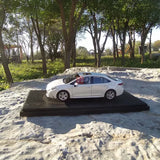 White diecast model car on black display base, side view