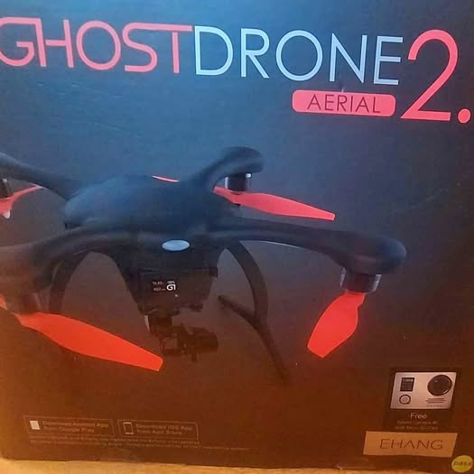 Black quadcopter drone with red propeller arms and central camera module