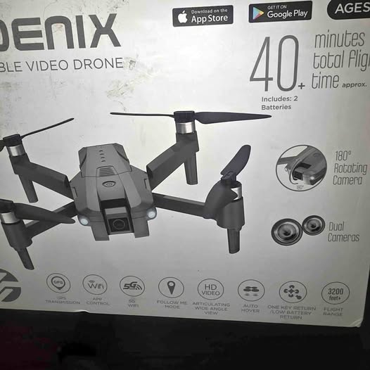 Gray quadcopter drone with attached camera and four propellers.