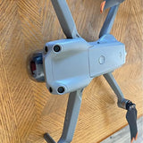 Light gray quadcopter drone with front camera and four folded propeller arms