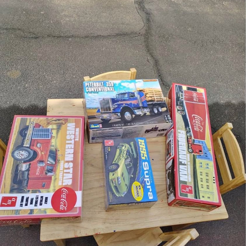 Diecast vehicle toys in boxes with trucks, mounted on a wooden display stand