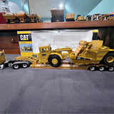 Yellow CAT diecast construction truck with loader arms on flatbed trailer