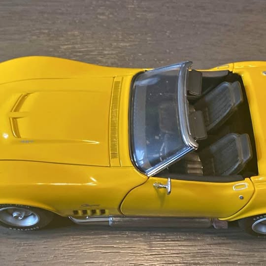 Yellow 1:18 diecast 1969 Corvette convertible with open roof, side view.