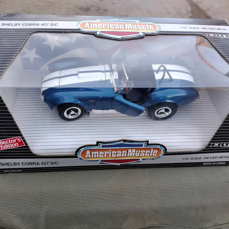 Blue diecast Shelby Cobra 427 S/C model with white racing stripes and chrome wheels