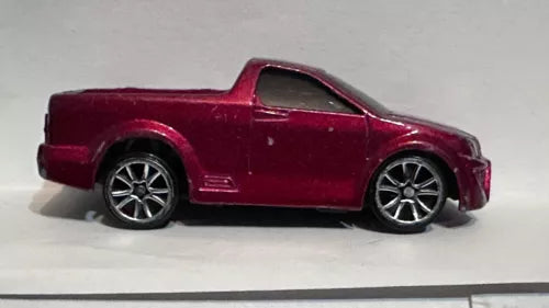 Maroon diecast pickup truck model with black wheels, side view