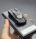 Black and silver diecast sports coupe model on display box, front hood detail.