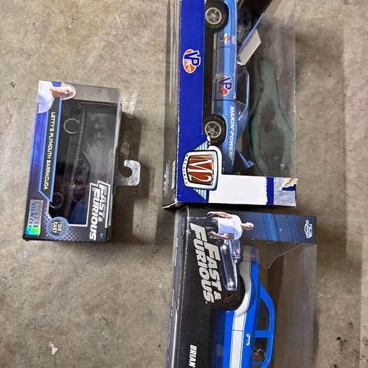 Blue diecast car toy in retail box, black accents and visible logo