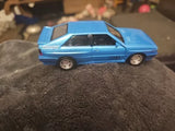 Blue 1/36 scale diecast toy car with gray wheels, side view