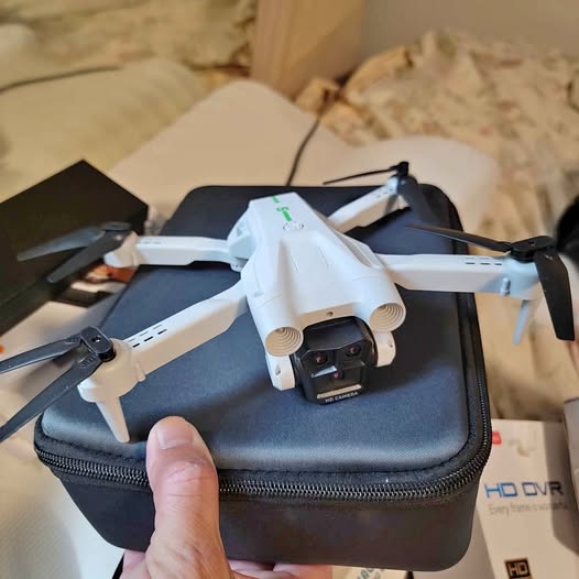 HD camera quadcopter drone with front lens and four propellers, resting on case