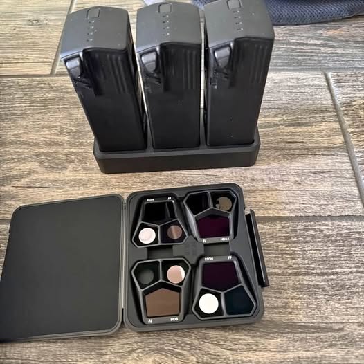 Drone accessory case with compartments and three batteries, plus cables and adapters
