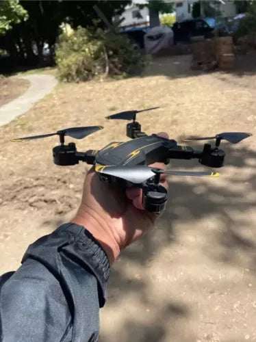 RC drone with mounted camera, held in a hand, visible propellers and front lens