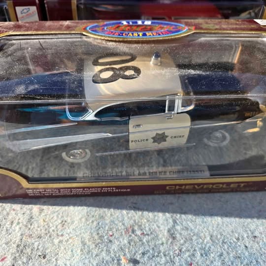Diecast police car model, blue and silver, with front grille and badge