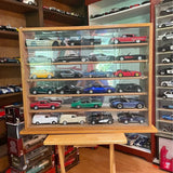 Wood display case with glass shelves holding multiple 1:24 diecast cars