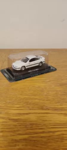 White diecast model car in a display case on a wooden base