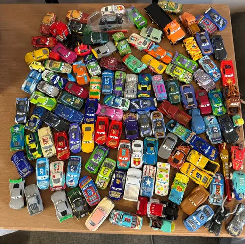Assorted 1:55 diecast race cars with colorful designs, in a cardboard tray