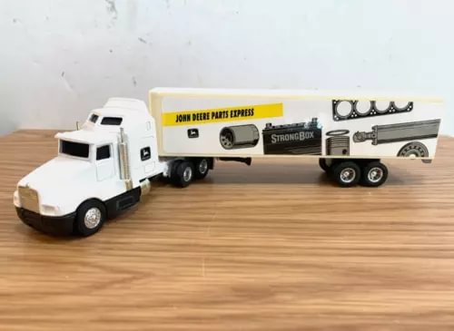 Diecast semi truck toy with white cab and green-yellow parts express trailer.