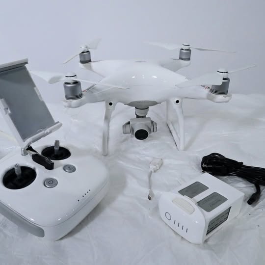 White quadcopter drone with controller, remote display, and spare batteries