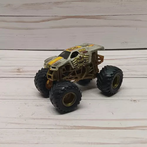 Diecast monster truck, brown and gray, four large tires, chunky frame, 1:64 scale