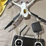 White quadcopter drone with propellers, front camera, and black remote