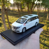 Die-cast minivan model in white with black grille, on display base, front 3/4 view