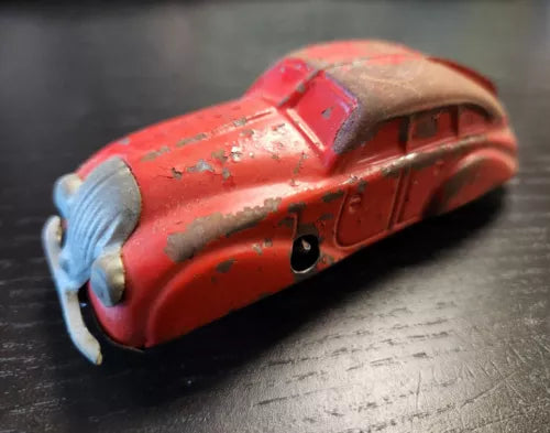 Red tin wind-up toy sedan with open grille, front three-quarter view