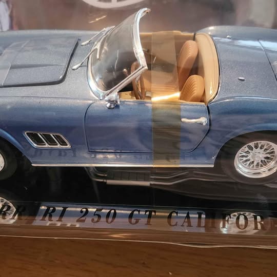 Blue diecast toy sports car with open driver's door and chrome wheels