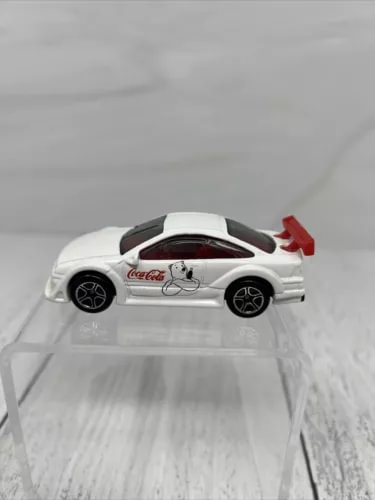 White Coca-Cola diecast toy car with black wheels on clear display base, rear view