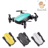 Foldable mini camera drone with teal body; shown with folded yellow, black, and white variants