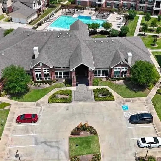 Aerial view of a house with pool, driveways, and parking spaces