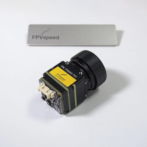 Thermal camera module with black cylindrical lens and yellow label, including board and connectors