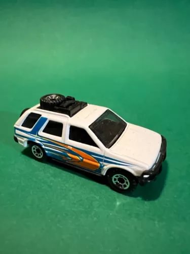 White diecast model car with blue and orange graphics, black wheels and roof rack