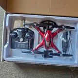 Red and black quadcopter drone with camera gimbal, packaged in a foam insert.