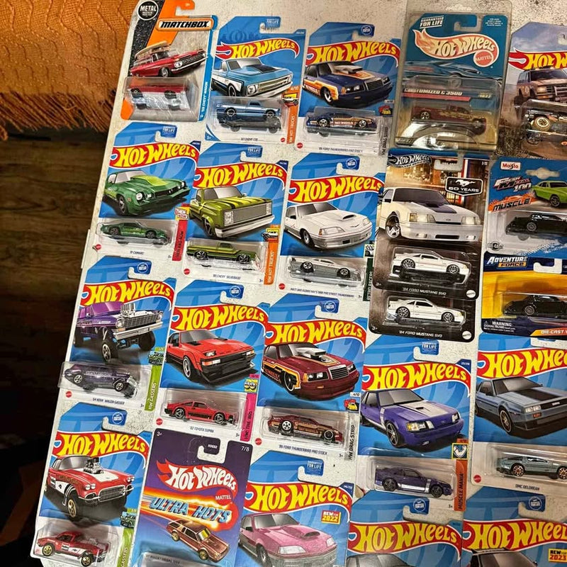 Assorted 1:64 diecast car models on retail blister packaging, Hot Wheels-style