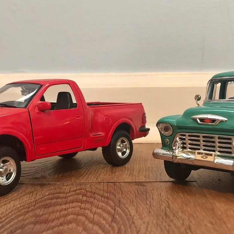 Red and green diecast pickup truck models, front three-quarter view