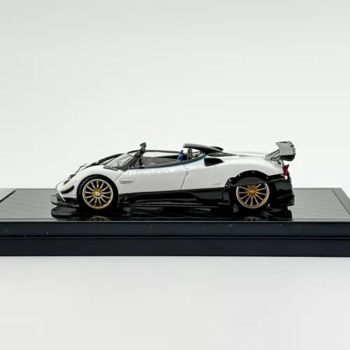 1:64 scale white metal sports car model with black accents and gold wheels, side view